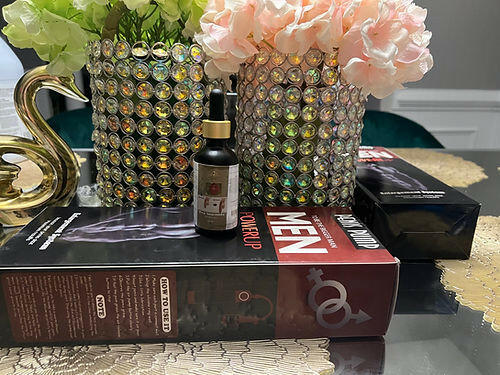 Anaconda oil male enhancement product bottle displayed with packaging on a table next to decorative flowers