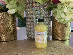 Bottle of 24K emu oil for hair growth placed on a decorative table between floral arrangements