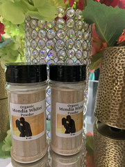 Two jars of organic mondia whitei powder with black lids on a reflective surface surrounded by decorative plants and containers